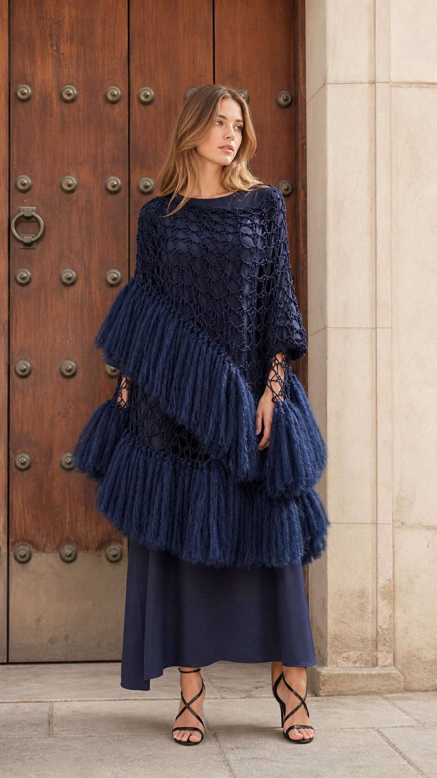 Front view of woman wearing navy blue tiered fringe crochet poncho top paired with a matching maxi skirt
