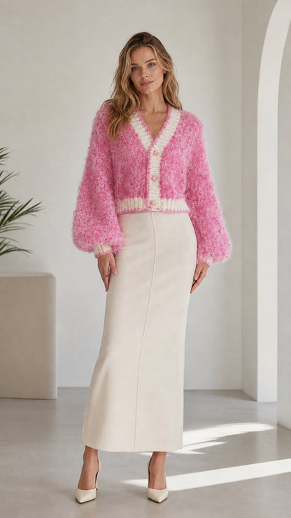 Front view of model wearing pink fluffy knit cropped cardigan with white maxi skirt