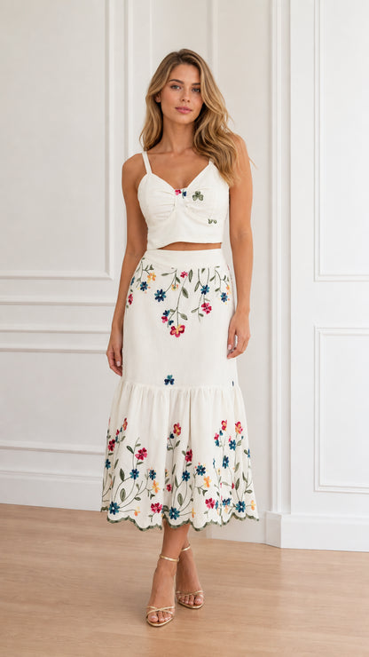 Front view of model wearing white floral embroidered crop top and tiered midi skirt set