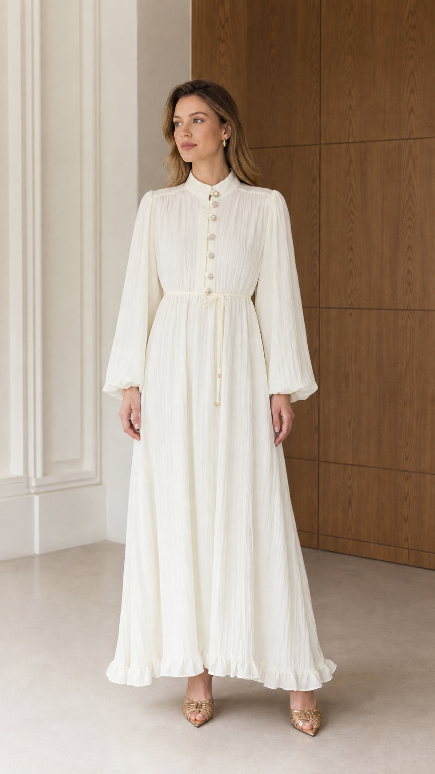 Full front view of a woman wearing the Cream White long sleeve pleated maxi dress with tie waist and stand collar