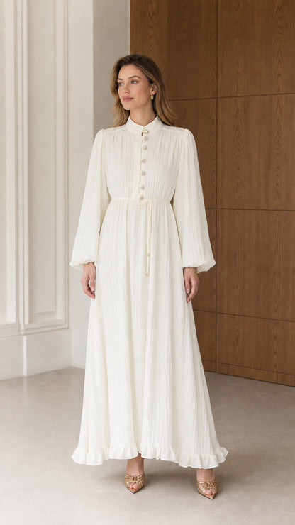 Full front view of a woman wearing the Cream White long sleeve pleated maxi dress with tie waist and stand collar