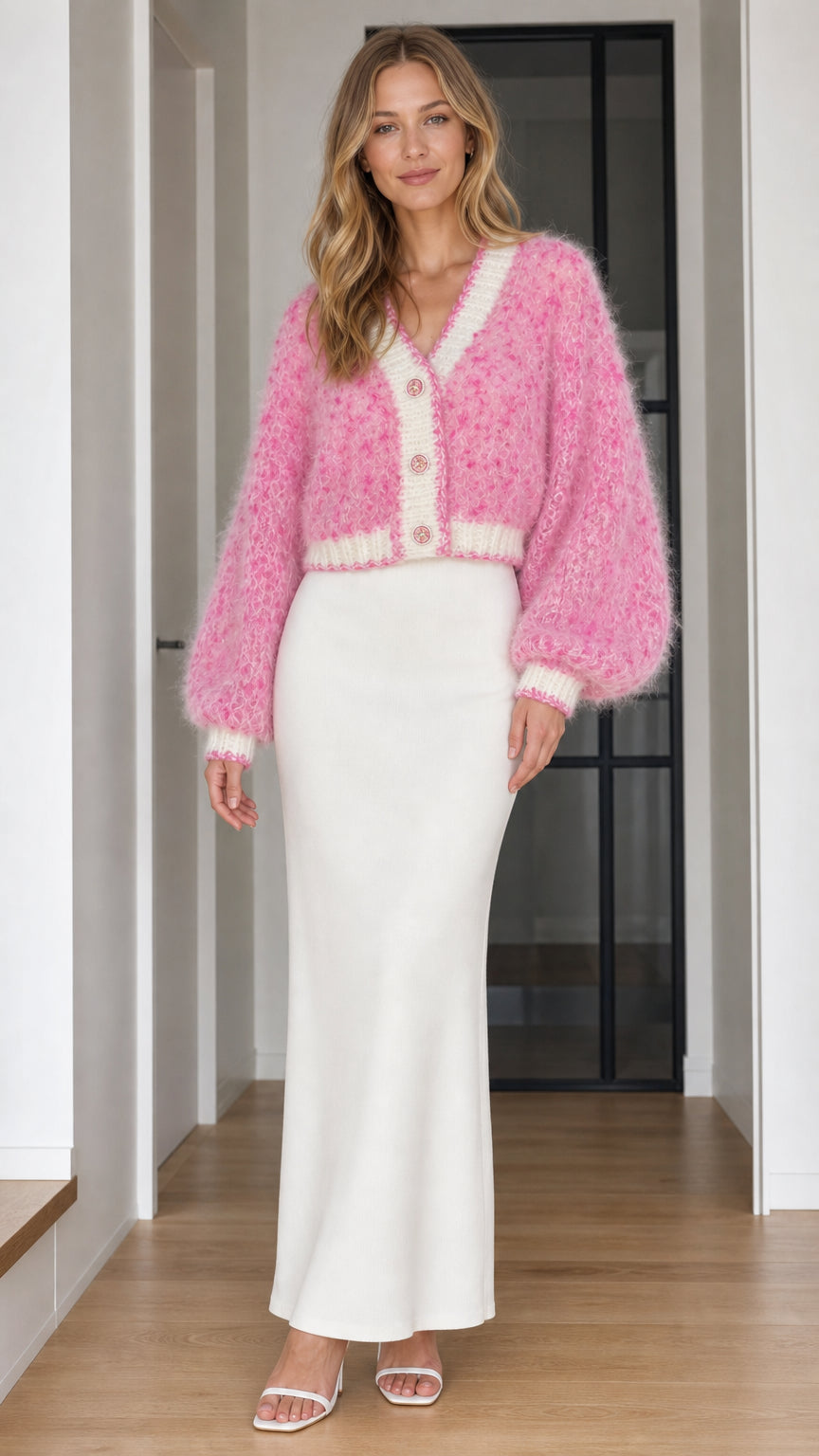 Model wearing pink fuzzy knit cropped cardigan with white maxi skirt, front view