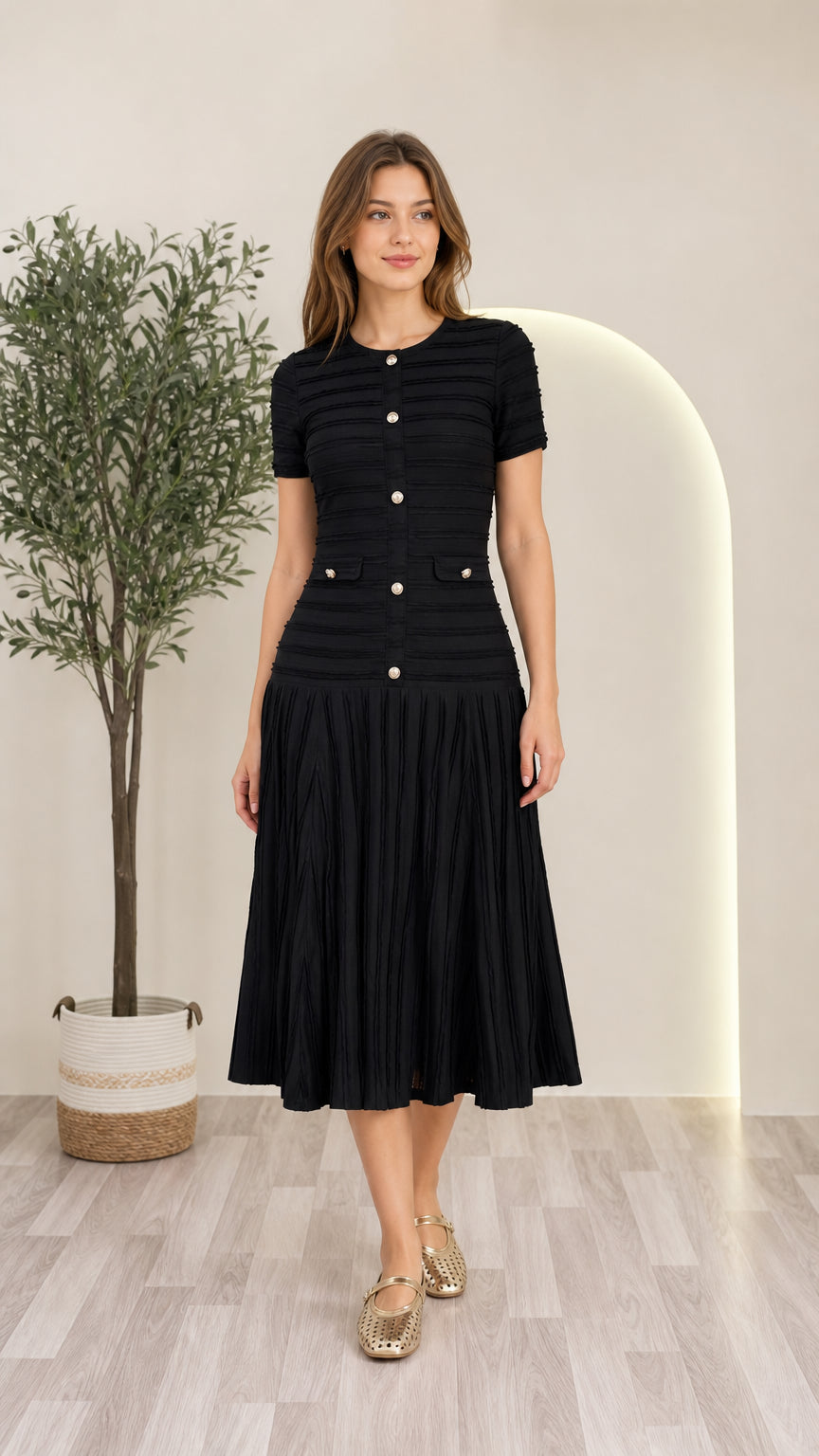 Front view of model wearing black short sleeve pleated knit midi dress