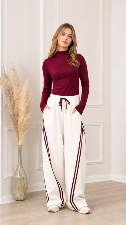 Front view of off-white wide-leg sweatpants with burgundy side stripes