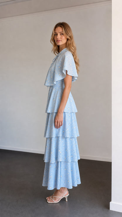 Side profile view of sky blue floral tiered capelet maxi dress