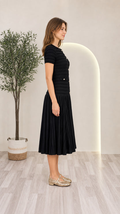 Side view of model wearing black short sleeve pleated knit midi dress