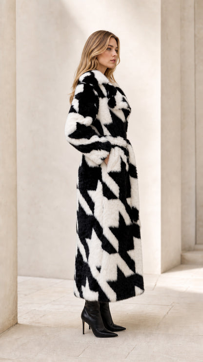 Side profile view of woman wearing long black and white houndstooth faux fur wrap coat