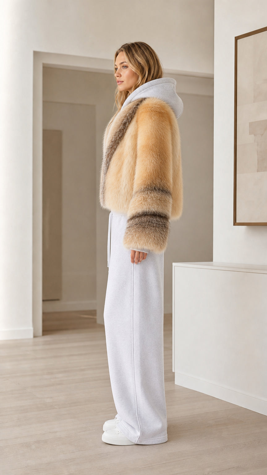Side view of camel faux fur cropped hooded jacket styled with white trousers