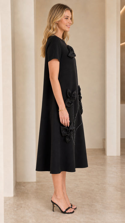 Side profile view of woman modeling Black 3D floral appliqué A-line swing dress