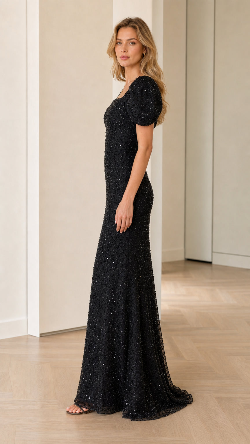 Side profile view of black floor-length sequin dress with puff sleeves