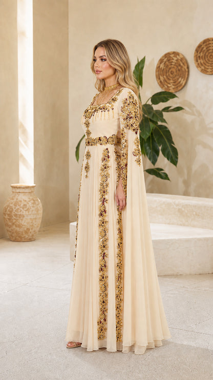 Side profile of model in elegant champagne embroidered cape dress