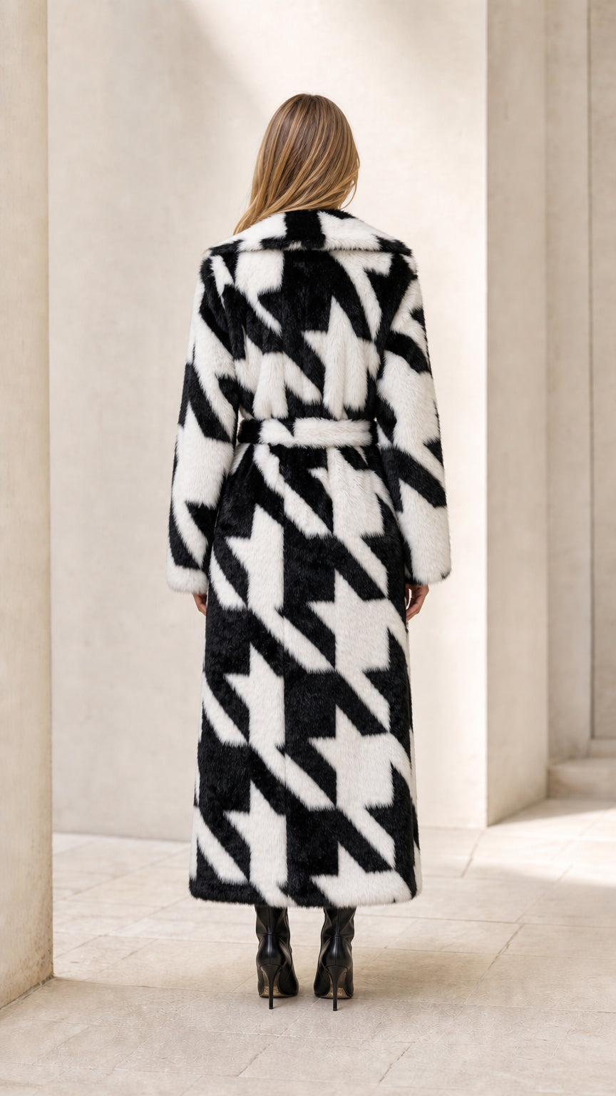 Back view of model in black and white houndstooth maxi faux fur coat with tie belt