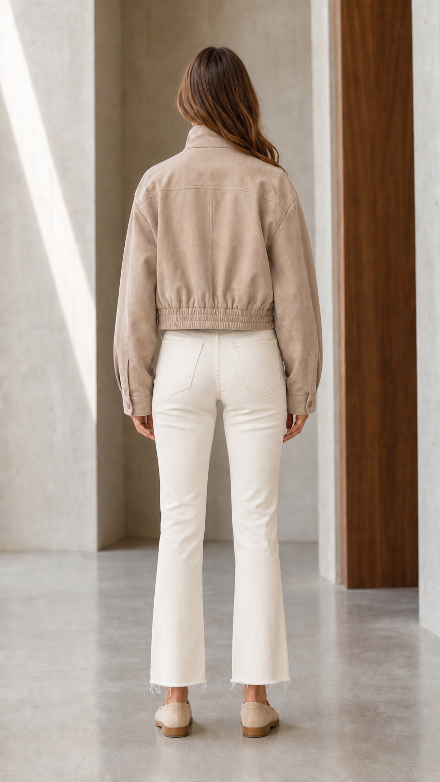 Back view of model wearing Khaki cropped jacket highlighting elasticized hem