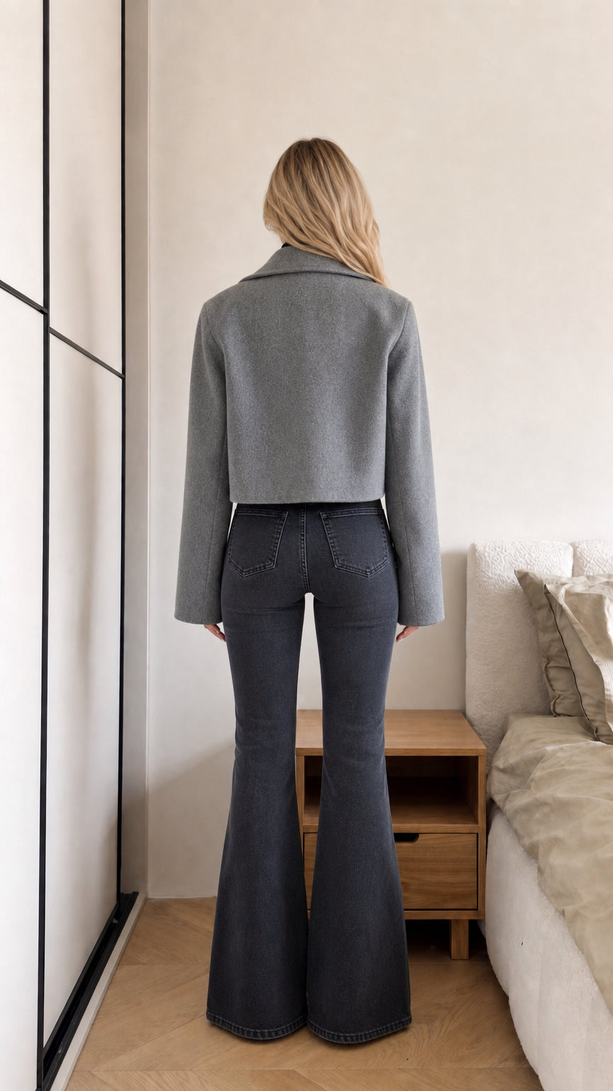 Back view of model wearing grey cropped coat highlighting clean shoulder line and waist-skimming hem