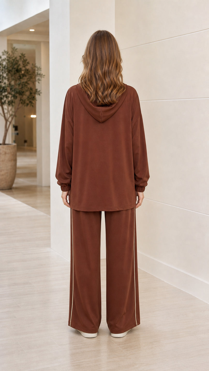 Back view of woman wearing brown hooded longline tunic top and wide-leg trousers