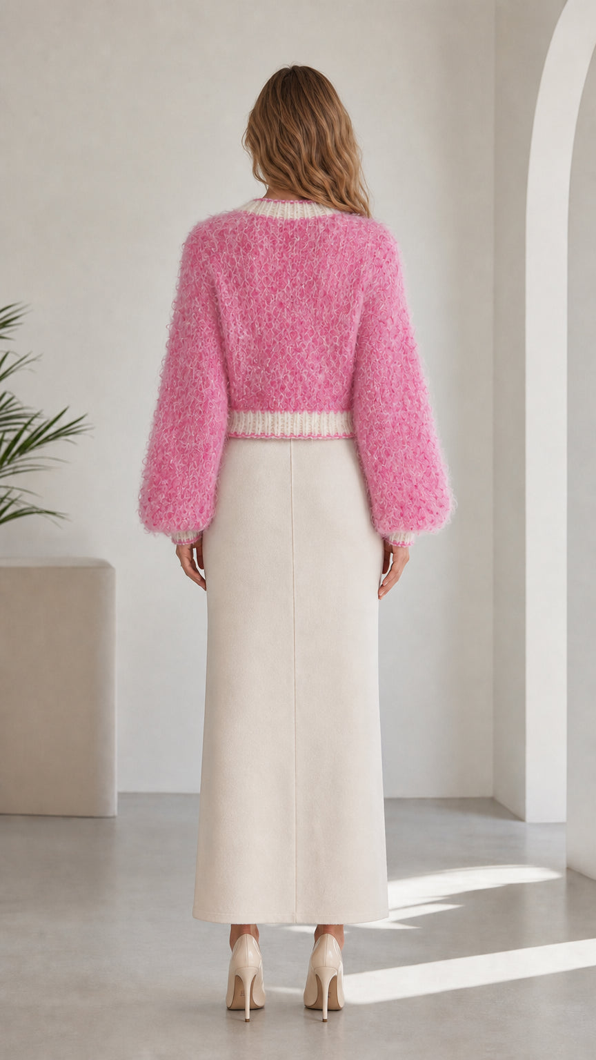 Back view of model in cropped pink fuzzy knit cardigan