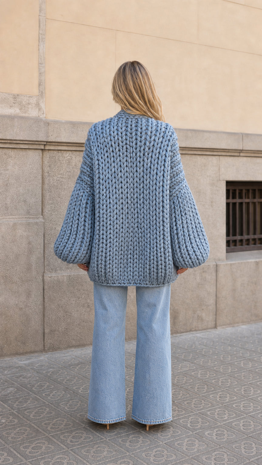 Back view of woman showing the mid-length hem and balloon sleeves of the slate blue knit cardigan