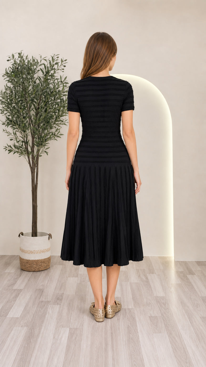 Back view of model wearing black short sleeve pleated knit midi dress