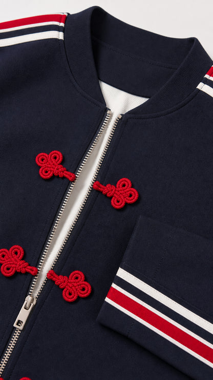 Close-up detail of navy blue jacket zipper, red frog buttons, and striped cuff