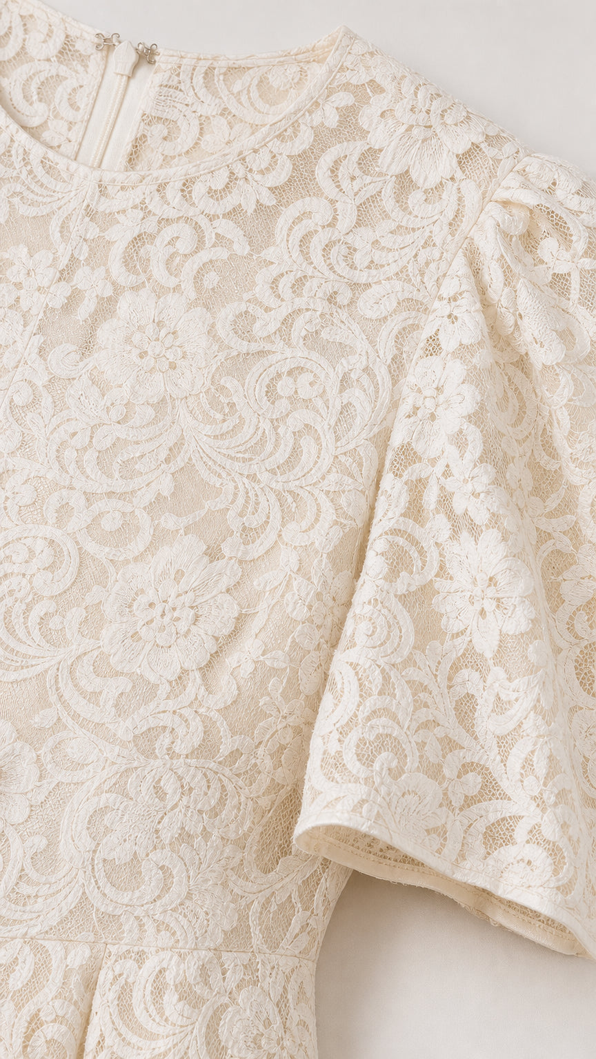 Close-up detail of white floral lace fabric and short puff sleeve construction