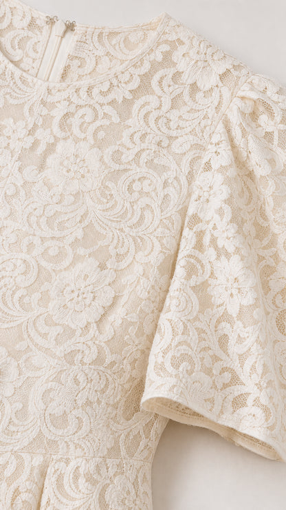 Close-up detail of white floral lace fabric and short puff sleeve construction