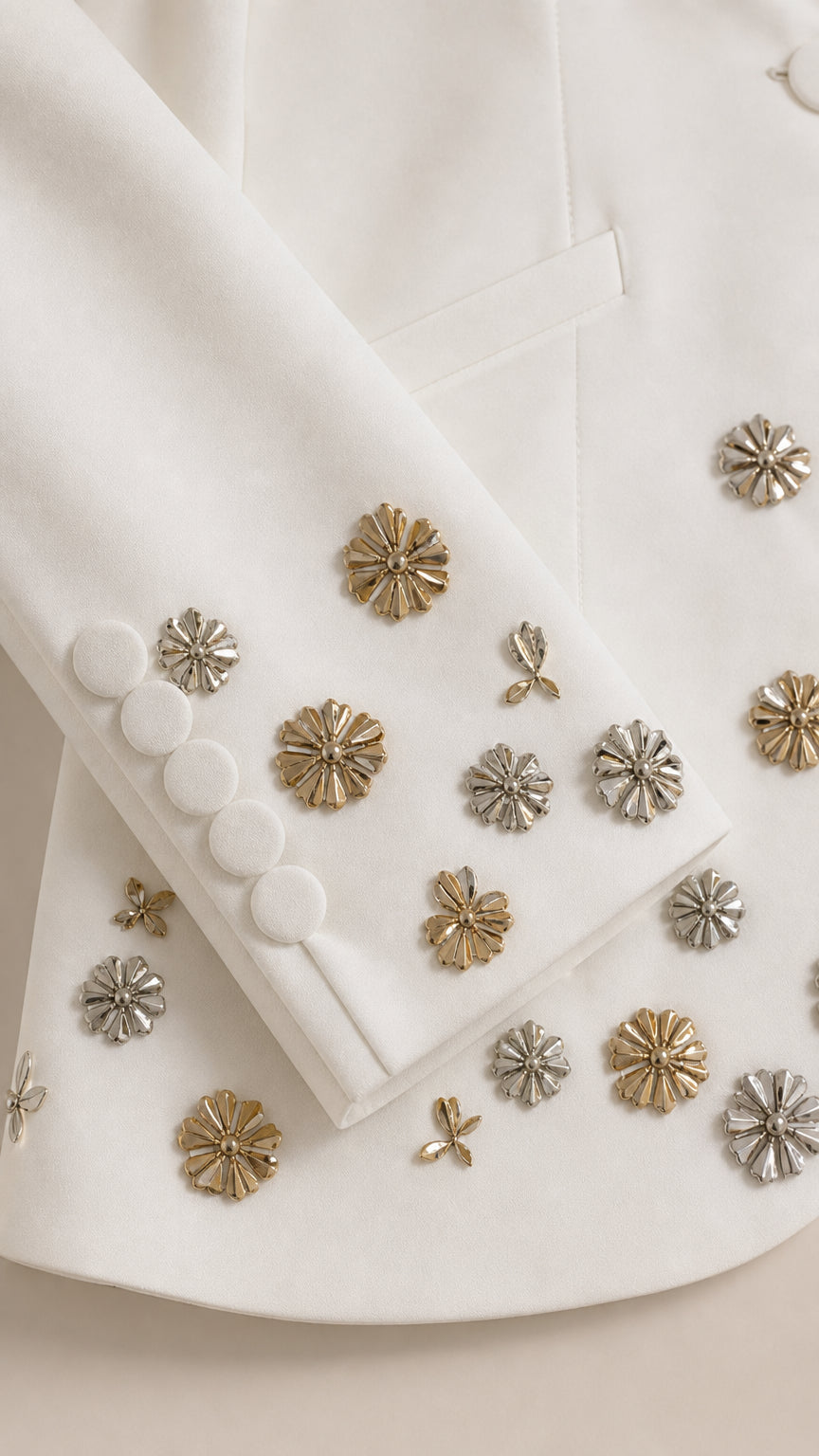Detailed close-up of fabric-covered sleeve buttons and metallic floral embellishments
