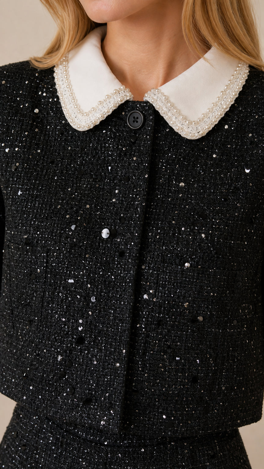 Close-up detail of pearl-embellished white contrast collar and textured black tweed fabric