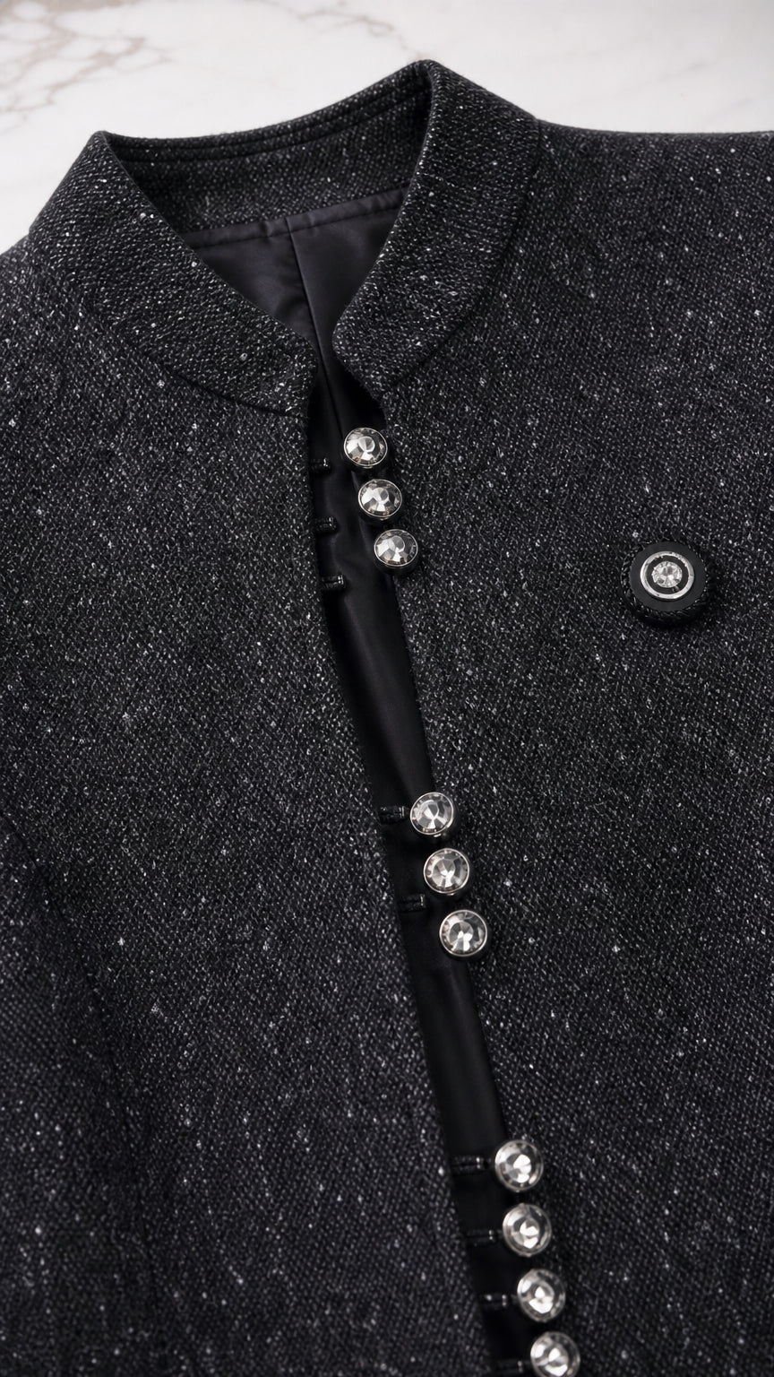 Close up of textured black tweed jacket with crystal button details and stand collar