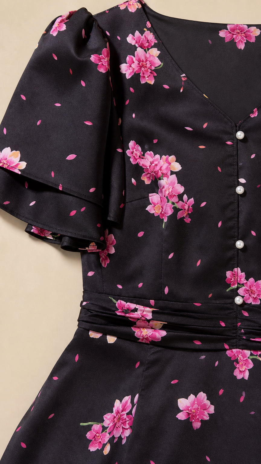 Close-up of floral print, flutter sleeve, ruched waist, and front buttons on black dress
