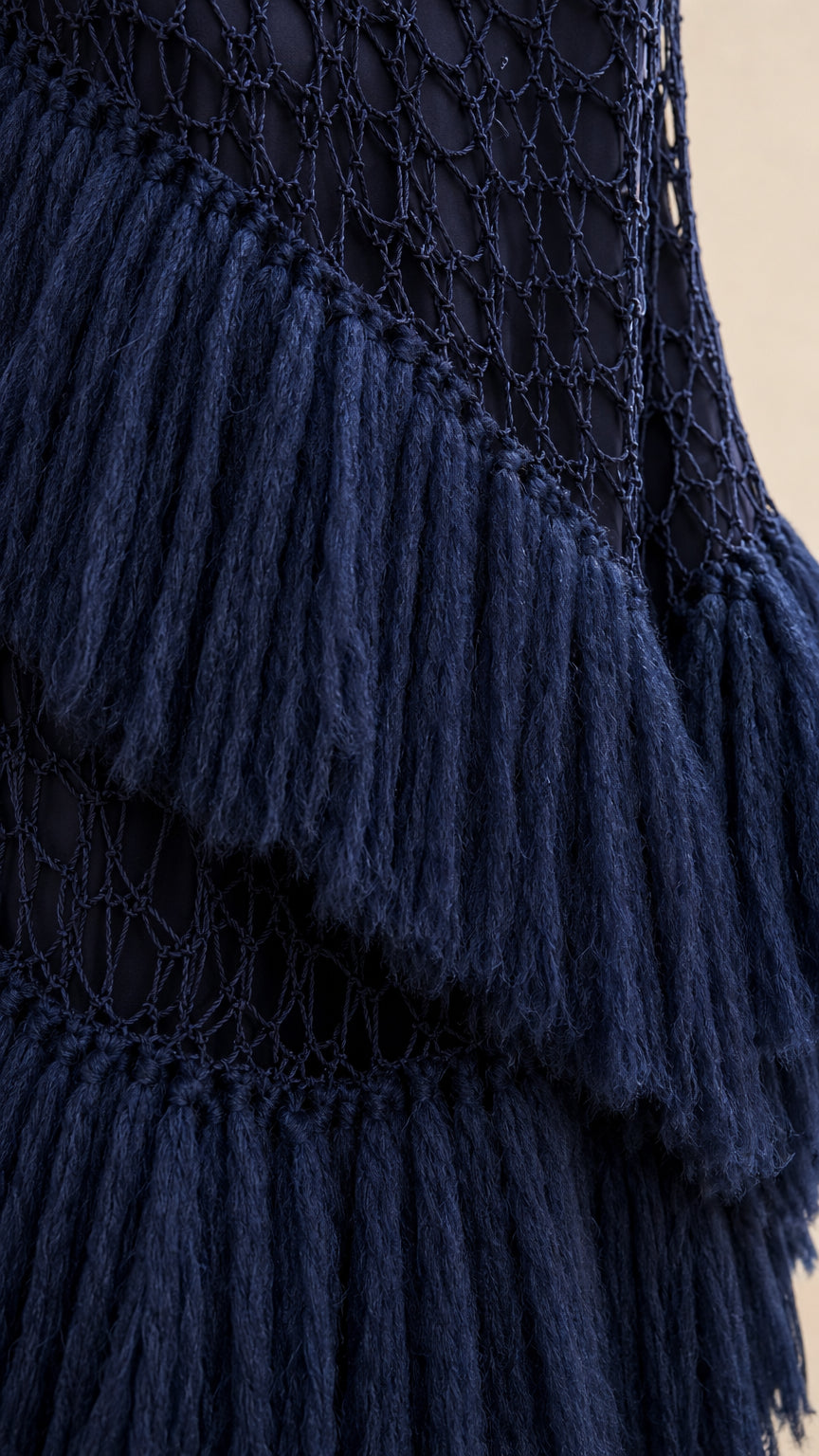 Close-up detail of navy blue open mesh crochet knit and plush layered fringe trim