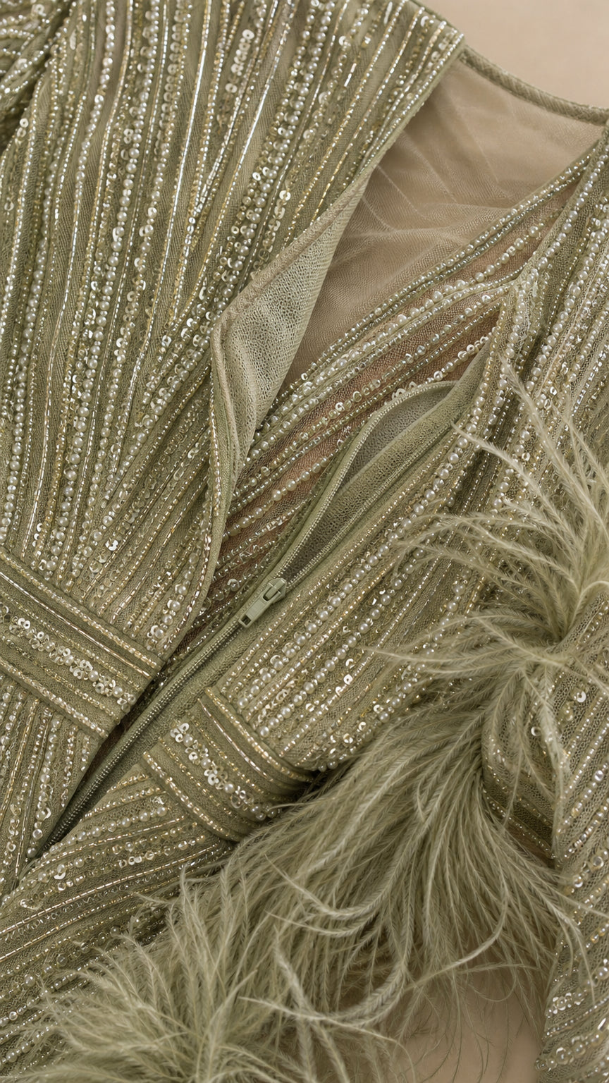 Close-up detail of sage green sequin embroidery, zipper, and plush feather trim