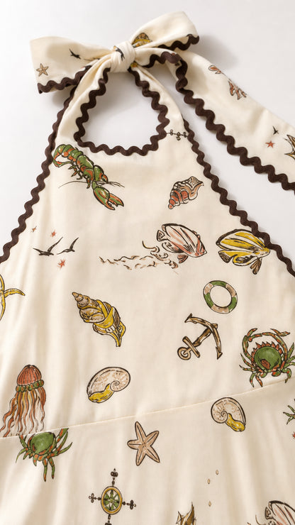 Close-up of cream halter neckline with ric-rac trim and detailed sea life illustrations