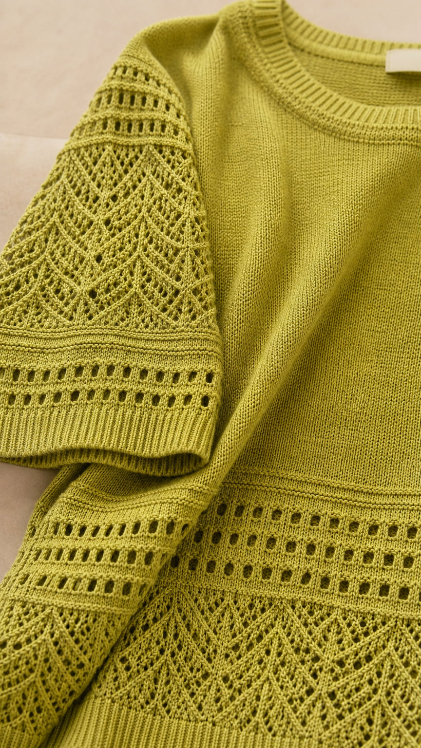 Close-up detail of geometric pointelle knit texture and sleeve trim