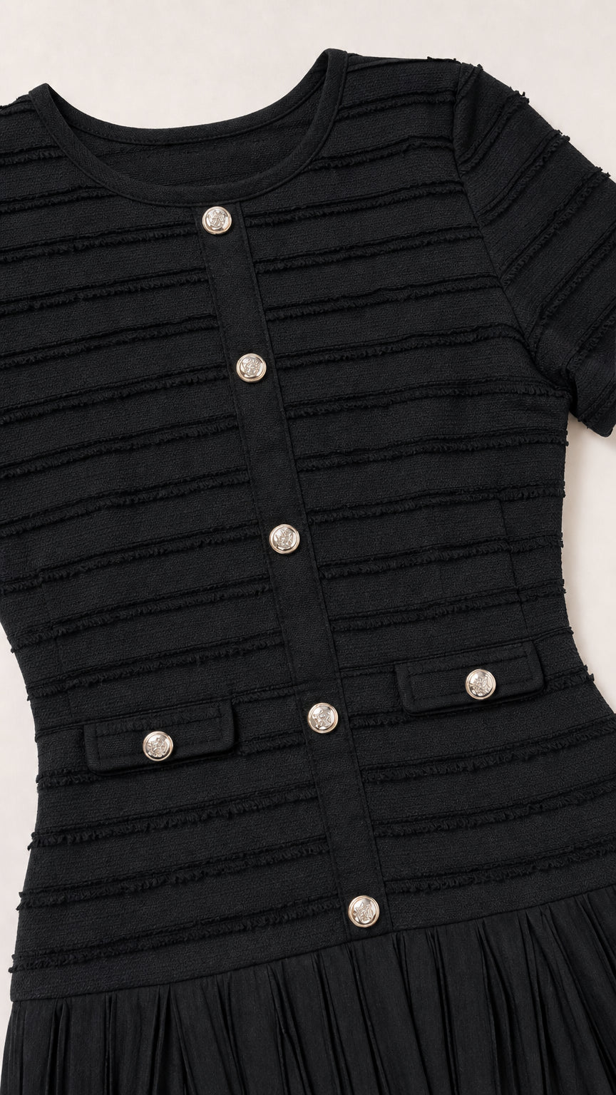 Close-up detail of black textured knit fabric and decorative metallic buttons
