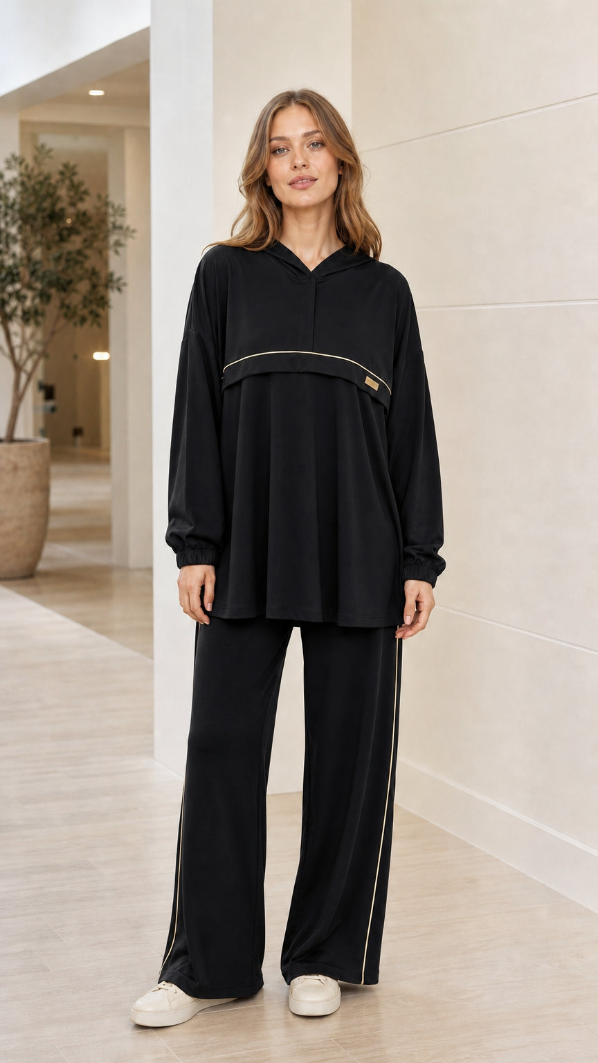 Front view of woman wearing black 2-piece hooded tunic and wide-leg pants loungewear set