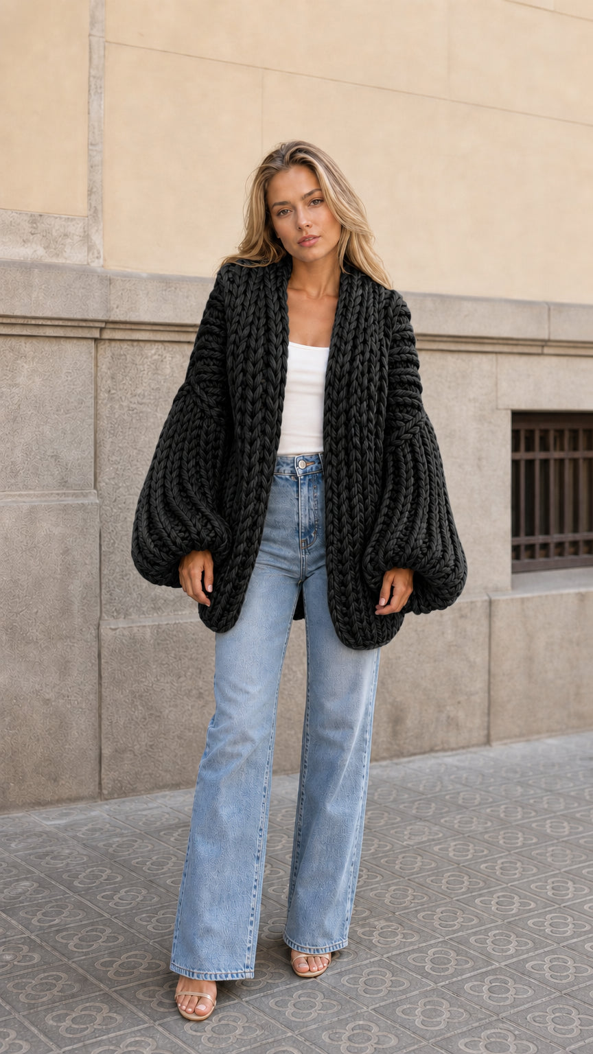 Front view of woman wearing black chunky knit balloon sleeve open front cardigan