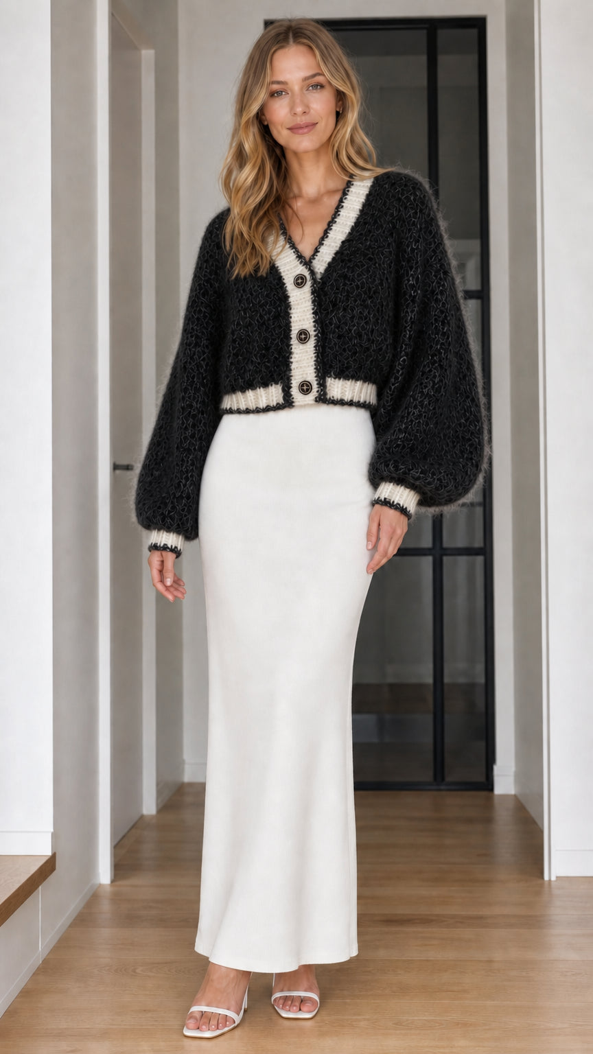 Model wearing black fuzzy cropped cardigan with white trim