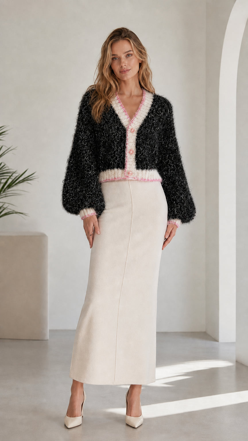 Model wearing black fuzzy knit cropped cardigan with contrast pink and white trim