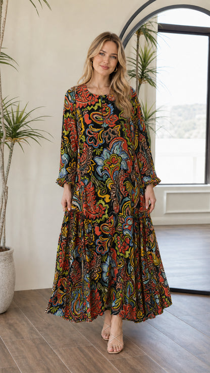 Front view of woman wearing black multi paisley long sleeve tiered maxi dress