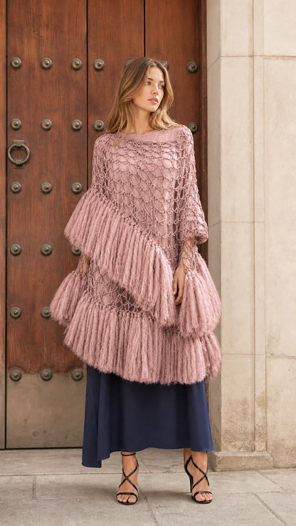 Front view of dusty pink tiered fringe crochet poncho top over a dark blue underlayer