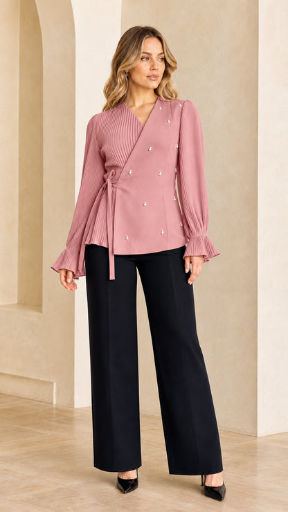 Model wearing dusty pink pleated wrap blouse with pearl details