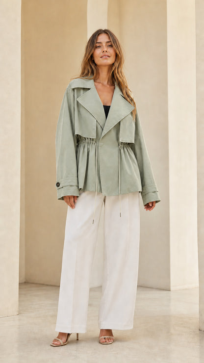 Front view of model wearing sage green short cinch-waist trench jacket