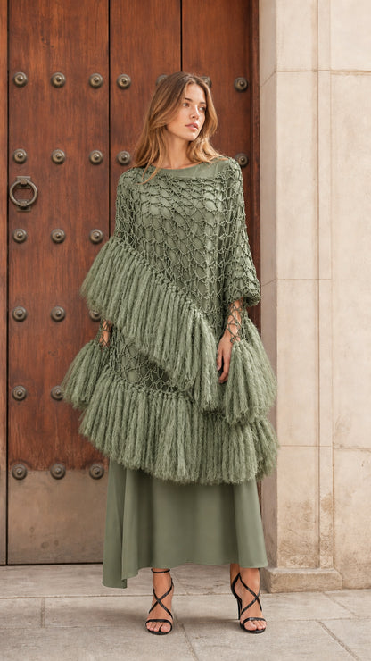 Front view of sage green tiered fringe crochet poncho top paired with a tonal olive maxi skirt