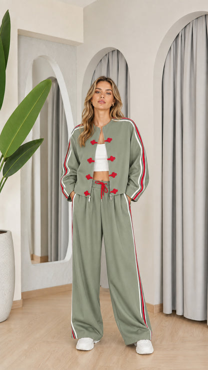 Model wearing sage green two-piece tracksuit set with red accents